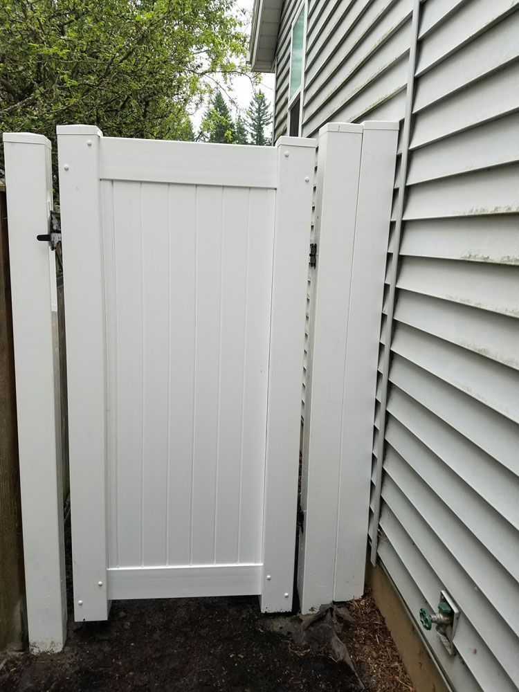 A white gate is sitting next to a white house