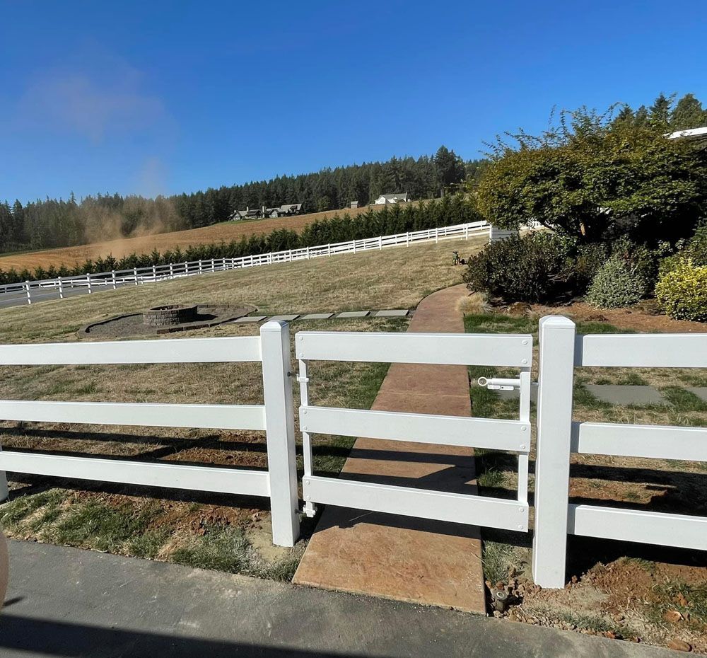 A white fence with a gate leading to a field