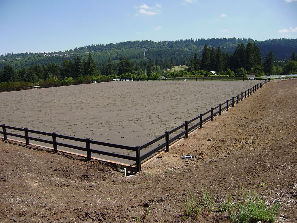 A large dirt field with a vinyl fence around it