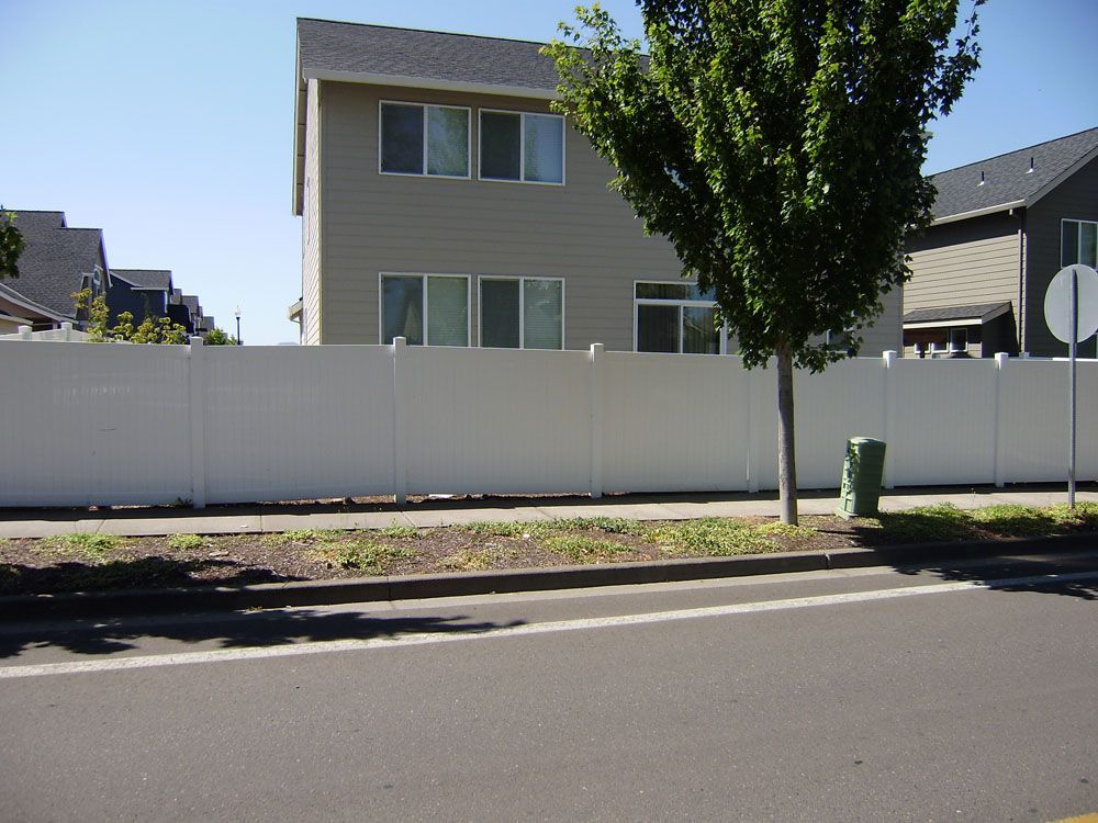 A house with a white fence and a tree in front of it