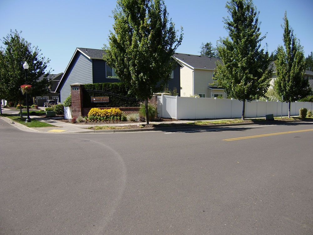 A white fence surrounds a house in a residential area