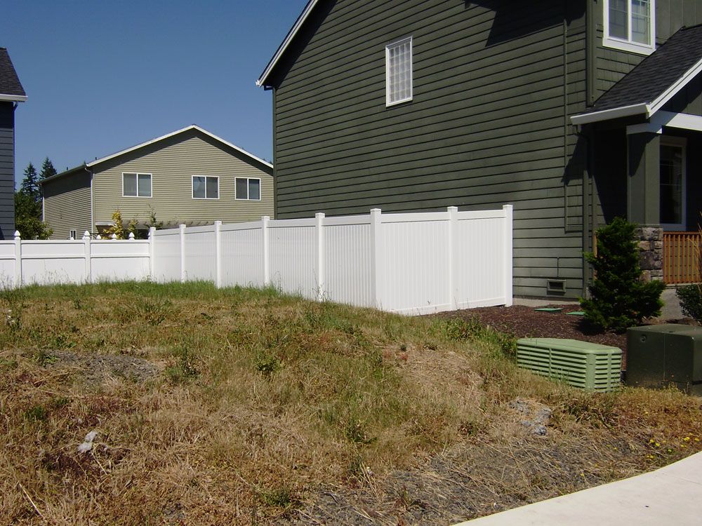 A white fence is in front of a green house
