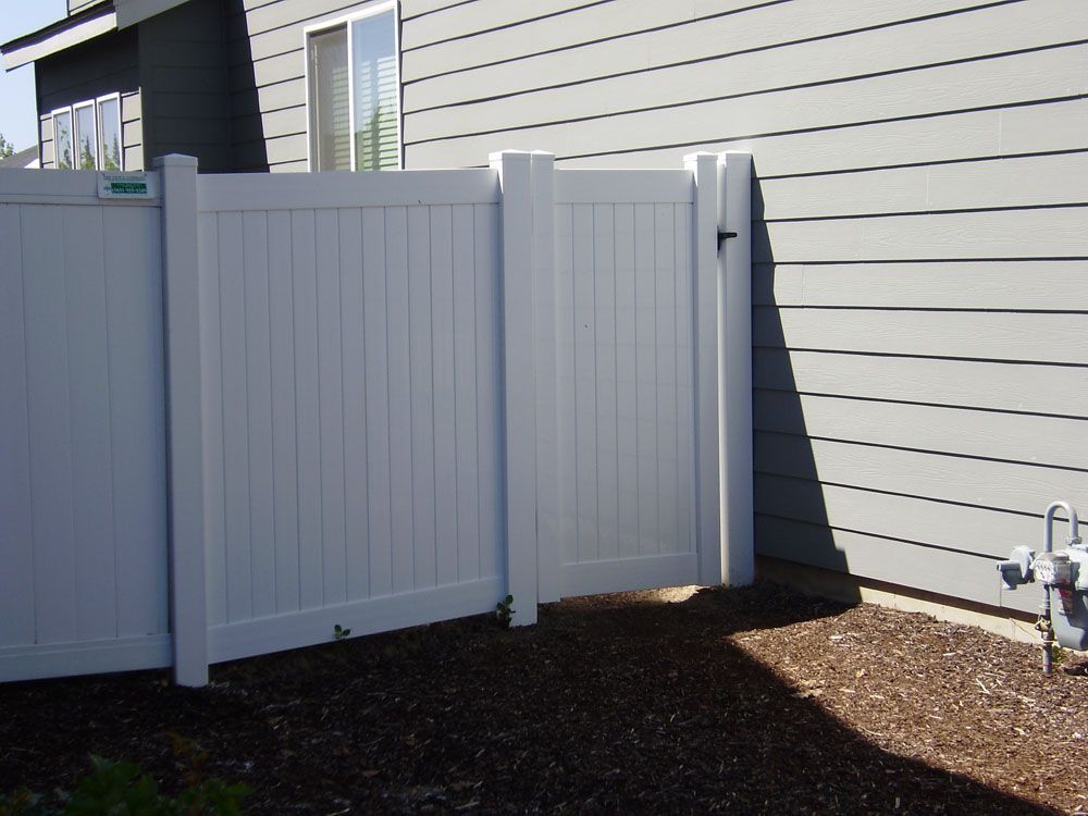 A white fence with a gate in front of a house