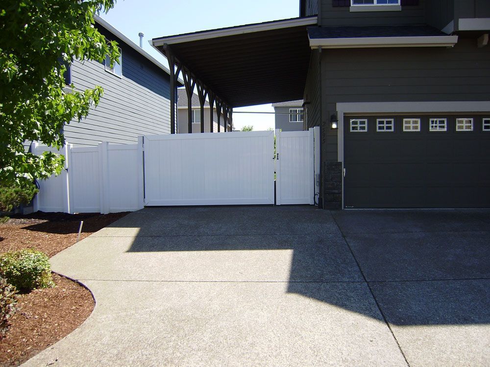 A house with a white fence and a black garage door