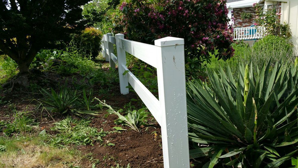 A white fence is in the middle of a garden