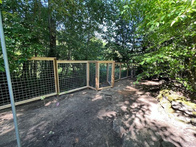 A wooden fence surrounds a dirt path in the woods