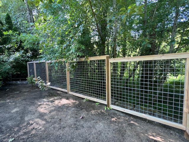 A wooden fence with a wire fence surrounded by trees