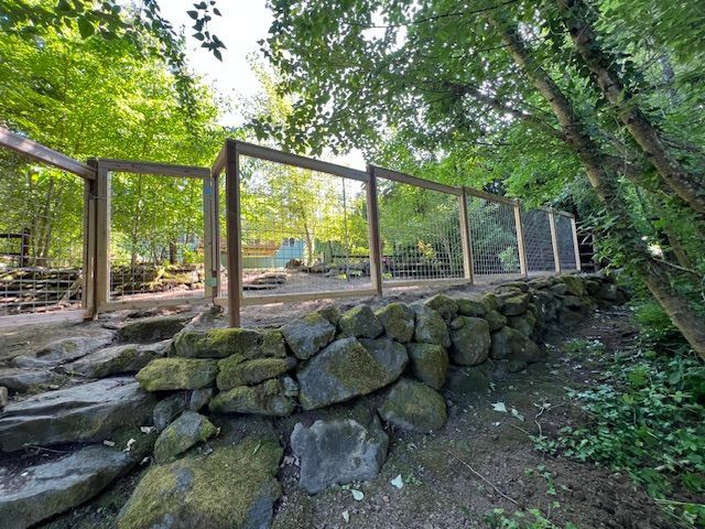 A wooden fence is surrounded by rocks and trees in a forest