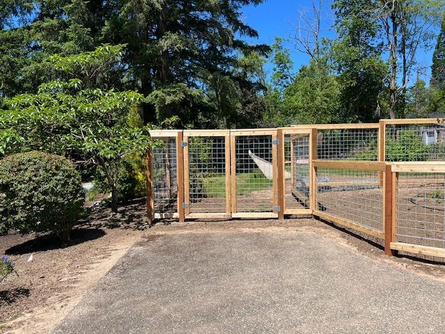 A wooden fence with a gate in the middle of a driveway