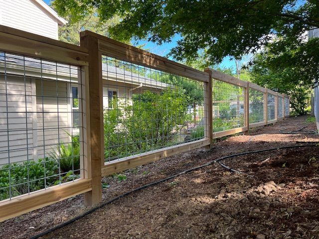 A wooden fence with a wire mesh in front of a house