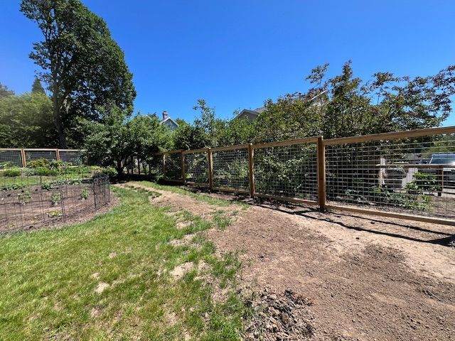 A wooden fence surrounds a lush green field