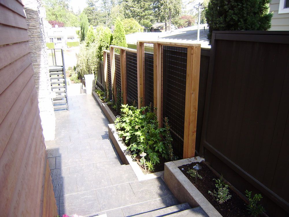 A wooden fence surrounds a walkway leading to a house