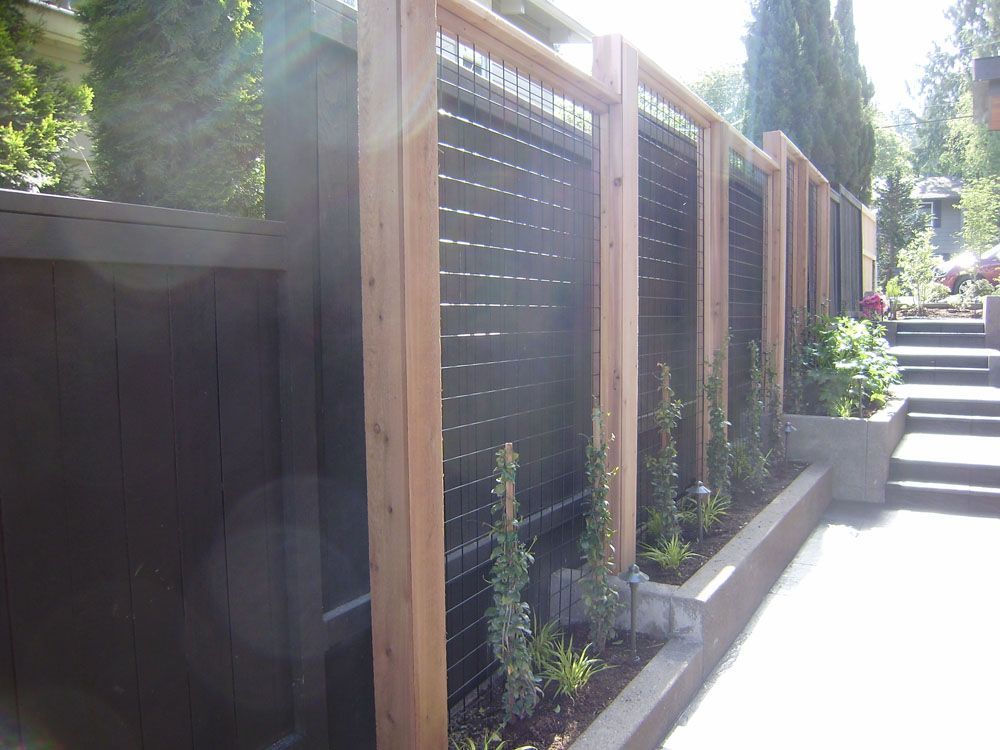 A wooden fence is surrounded by plants and stairs