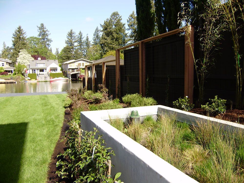 A fence surrounds a lush green yard with a lake in the background