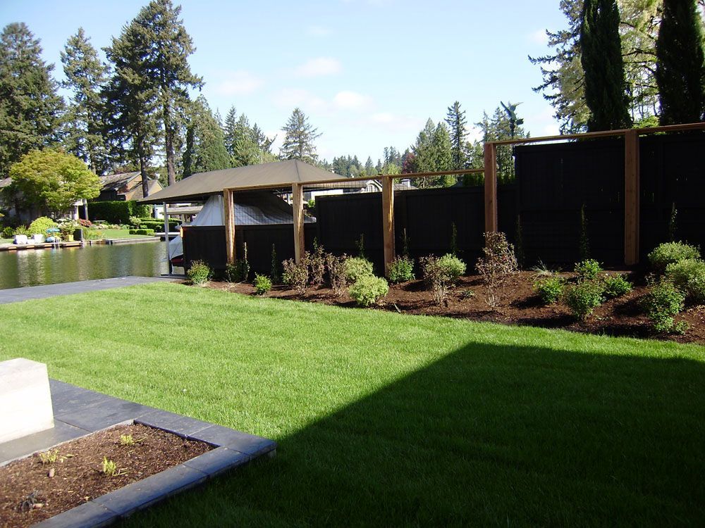 A lush green lawn with a black fence in the background