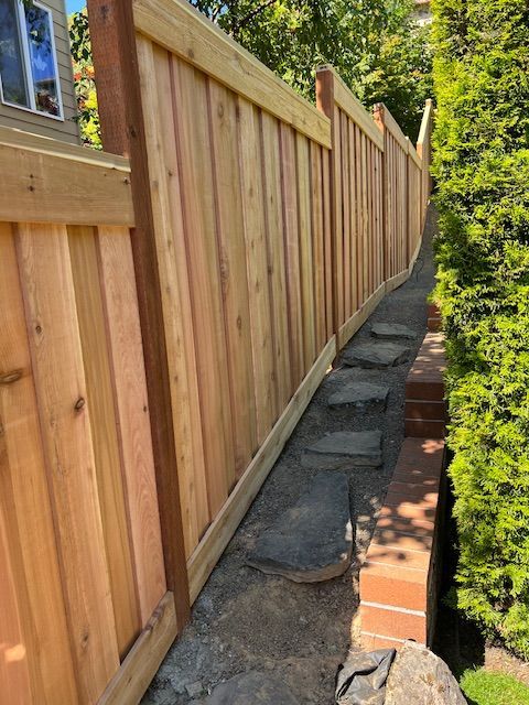 A wooden fence is sitting next to a stone walkway