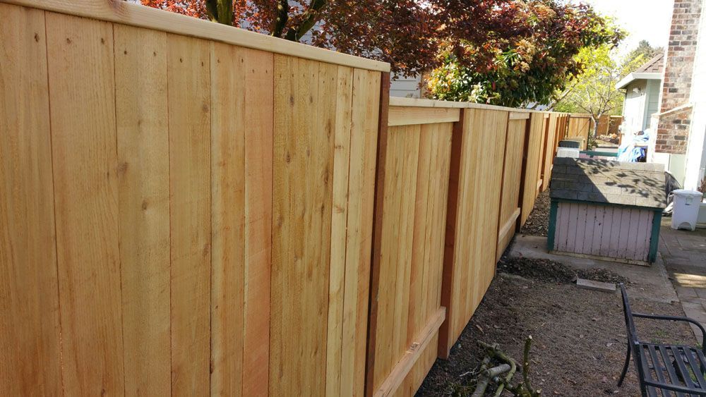 A wooden fence is in the backyard of a house