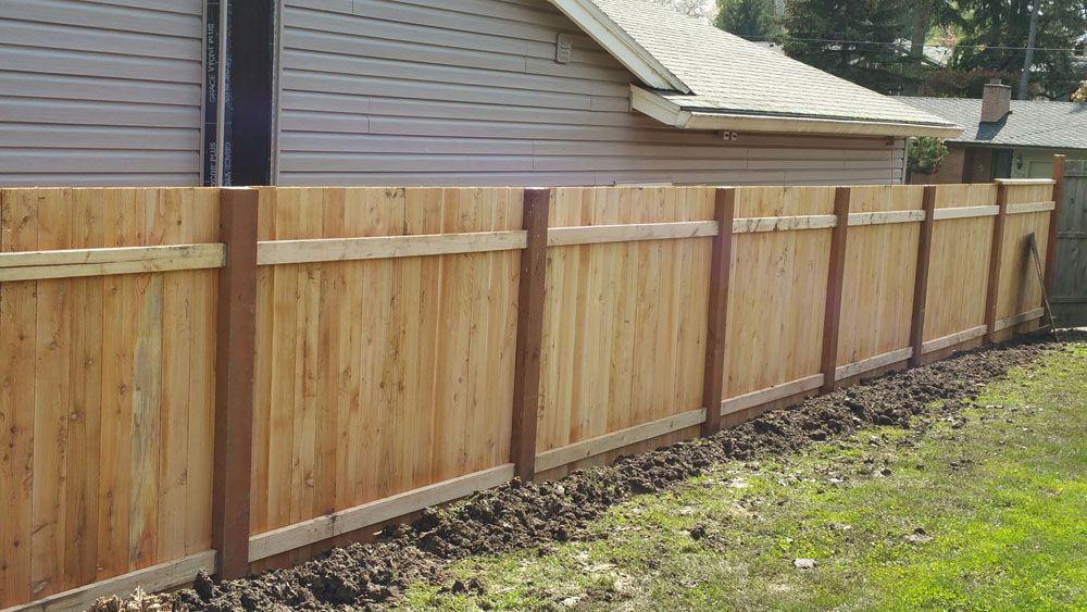 A wooden fence is sitting next to a house in a backyard