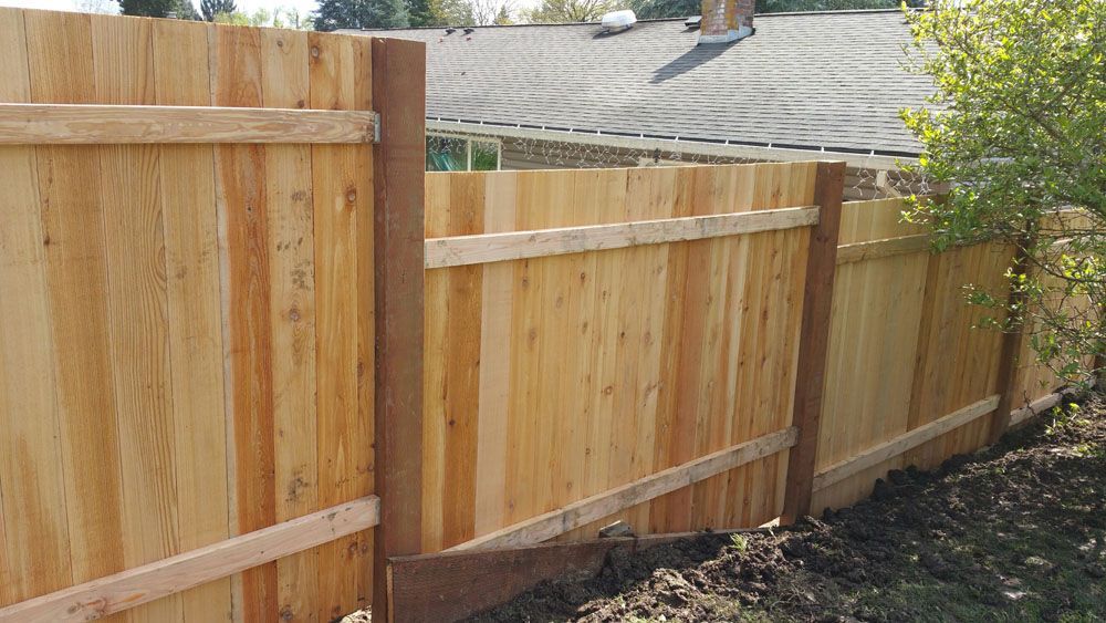 A wooden fence is sitting in the dirt in front of a house