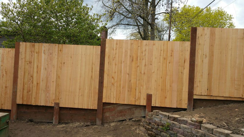 A wooden fence is being built in a backyard