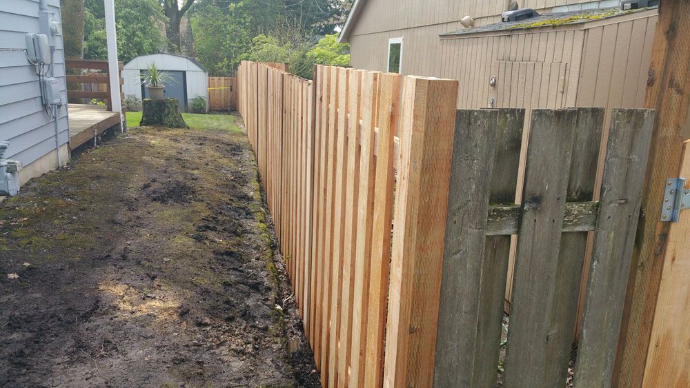 A wooden fence is being built in the backyard of a house