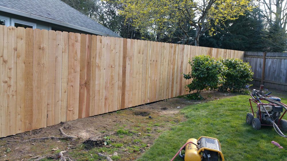 A wooden fence is being built in the backyard of a house
