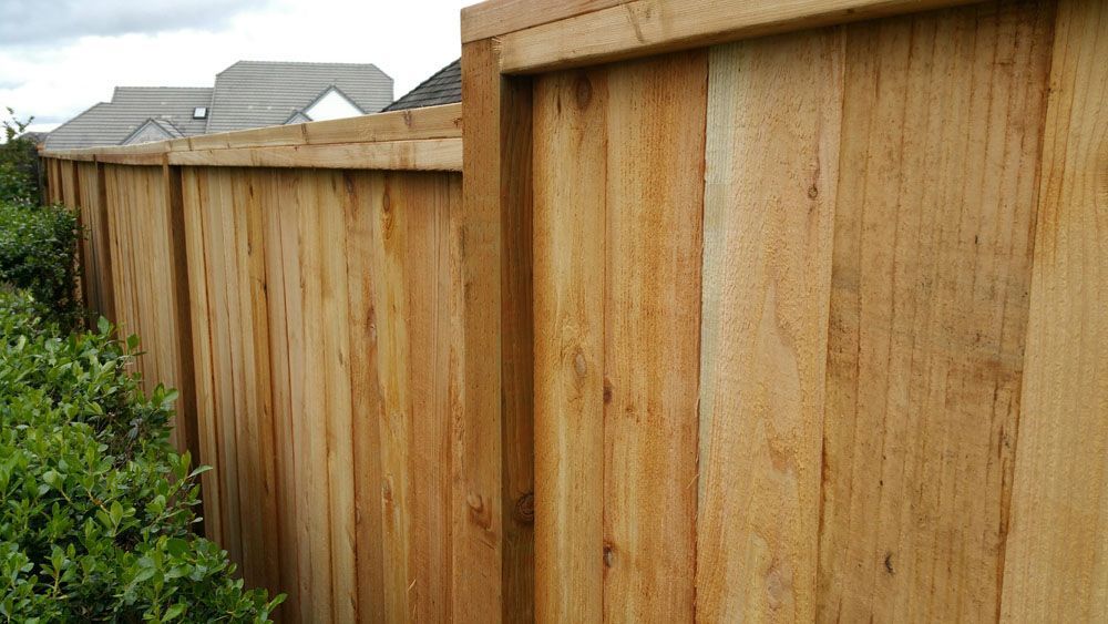 A close up of a wooden fence with a house in the background