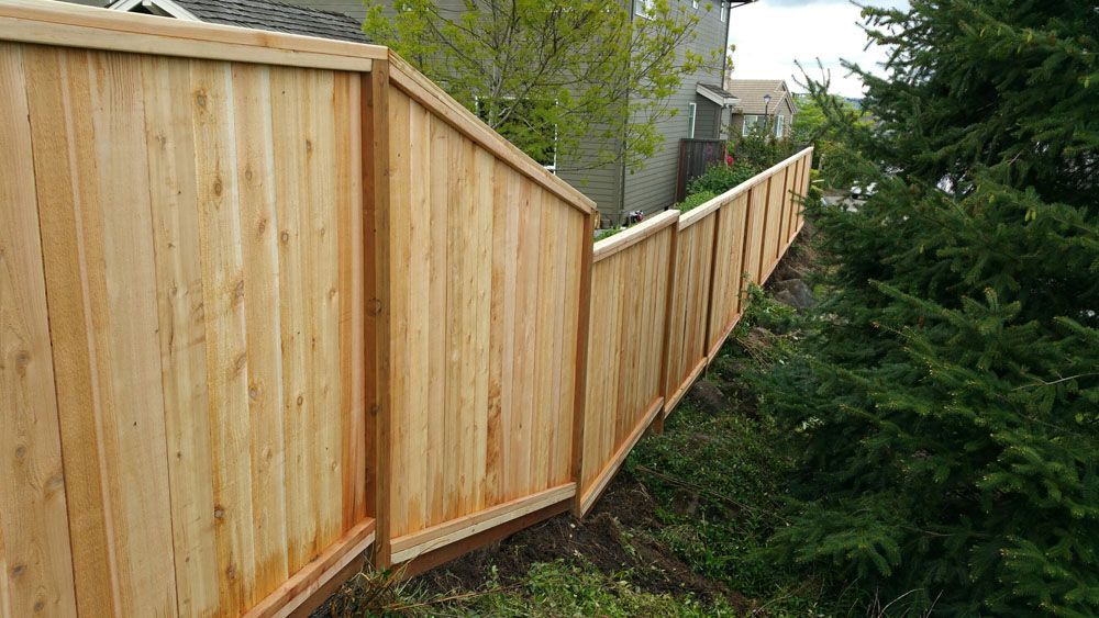 A wooden fence is sitting on top of a hill next to a house