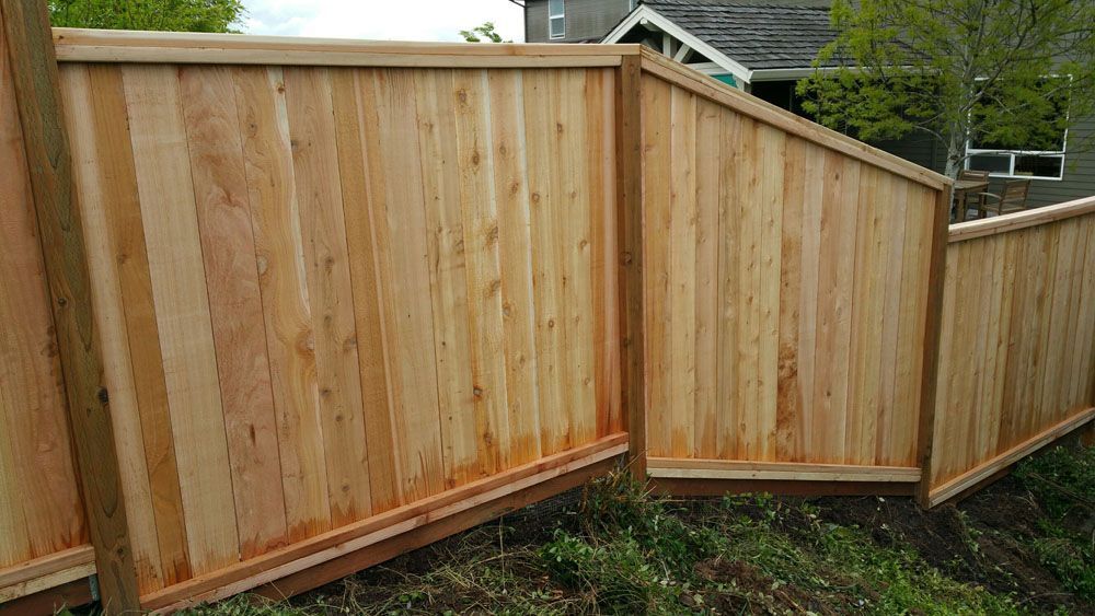 A wooden fence is sitting in the grass in front of a house