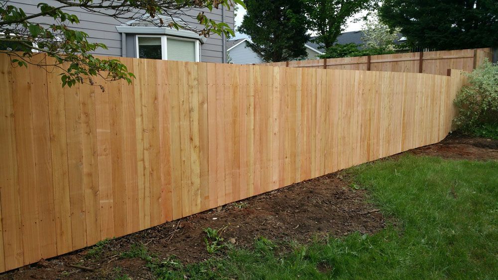 A wooden fence is in the backyard of a house