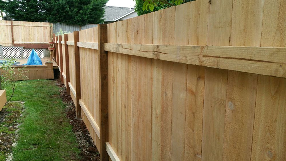 A wooden fence is surrounded by grass in a backyard