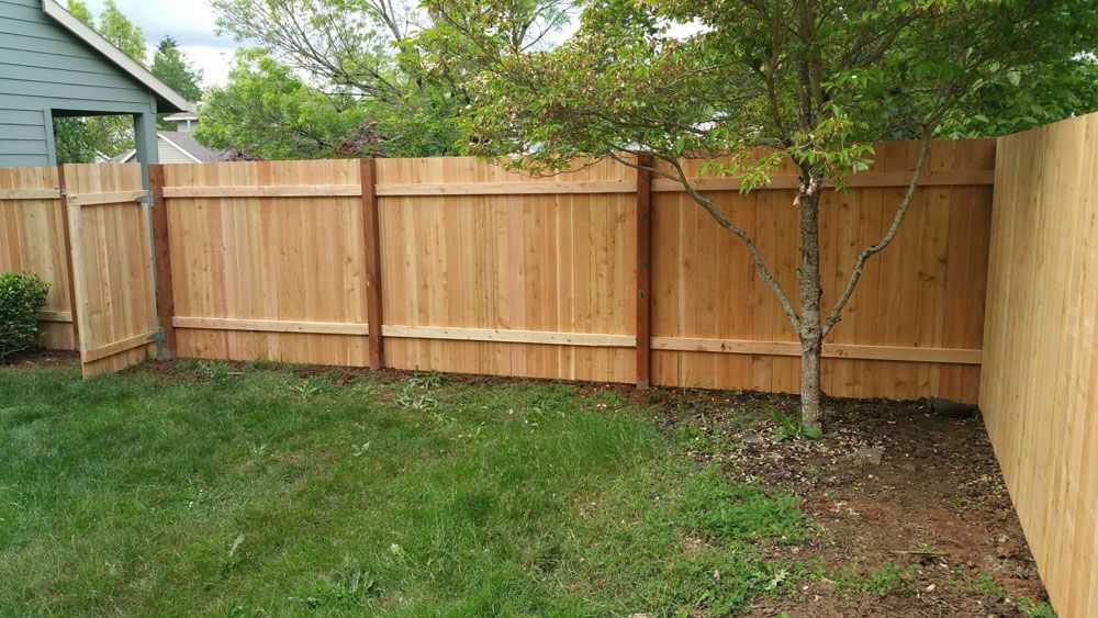A wooden fence is in the backyard of a house