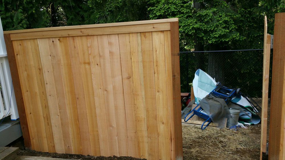 A wooden fence is sitting next to a pile of trash