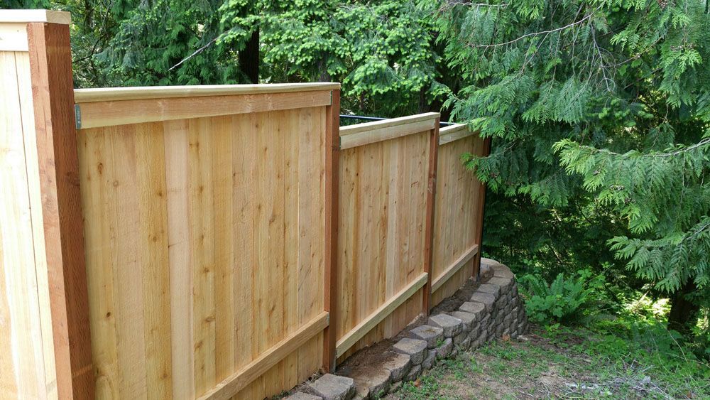 Trees and a stone wall surround a wooden fence