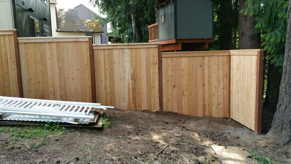 A wooden fence is being built in a backyard