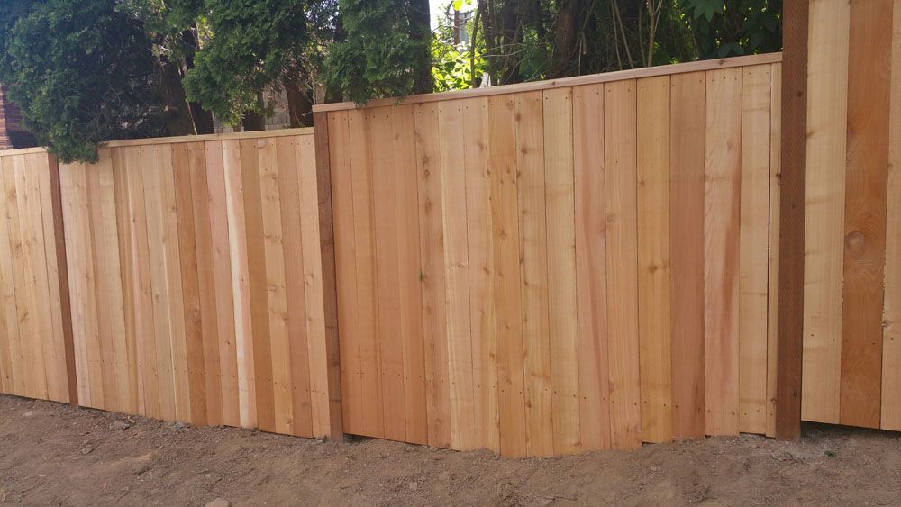 A wooden fence is sitting on top of a dirt field