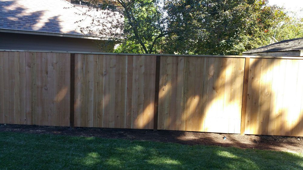 A wooden fence is in the backyard of a house