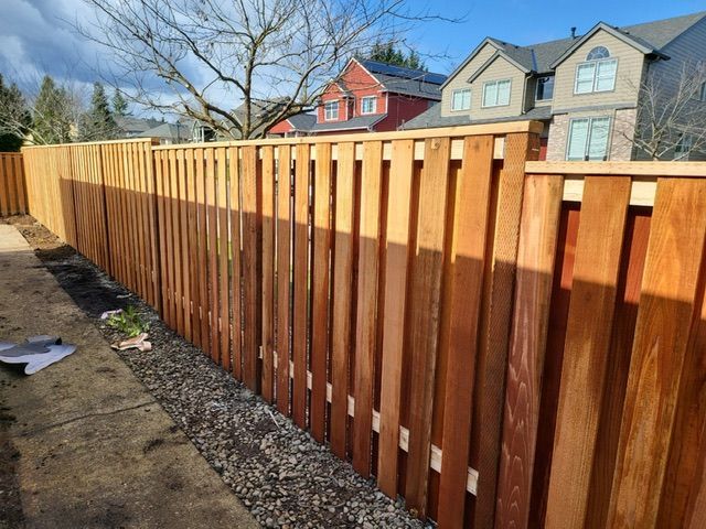 A wooden fence surrounds a backyard with houses in the background