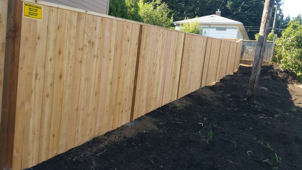 A wooden fence is sitting on top of a hill next to a house