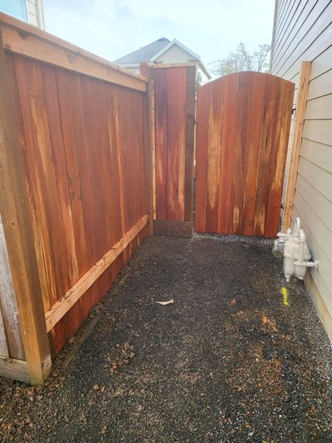 A wooden fence with a gate in the backyard of a house
