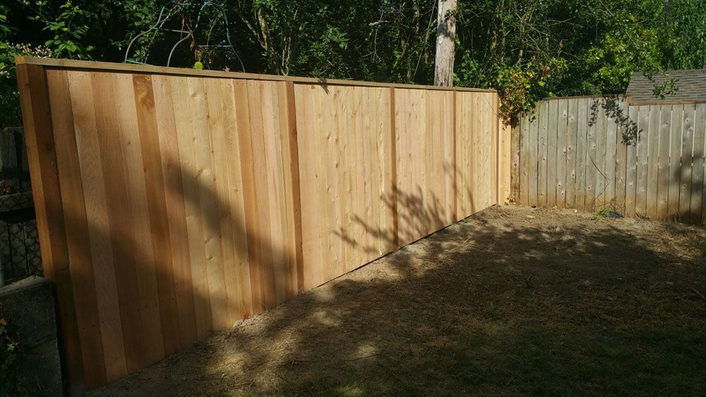 A wooden fence is in the backyard of a house