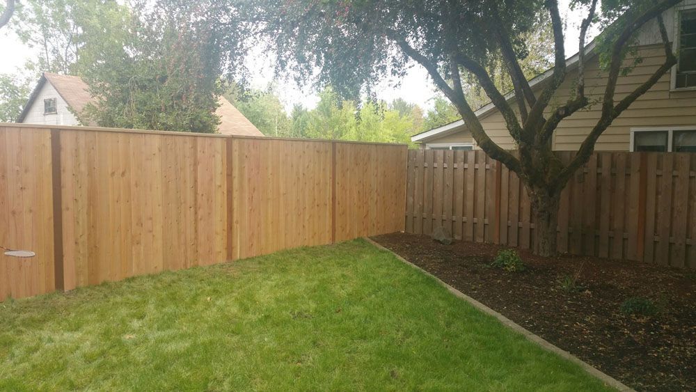 A wooden fence is in the backyard of a house