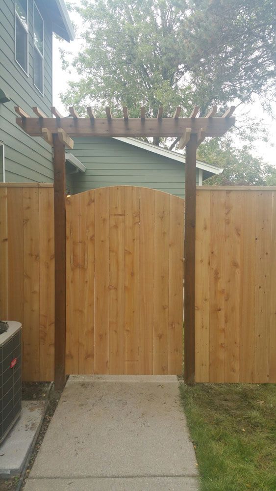 A wooden fence with a pergola in the backyard of a house