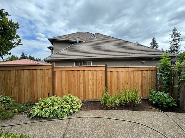 A wooden fence surrounds a patio in front of a house