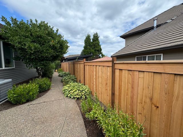 A wooden fence along a sidewalk next to a house
