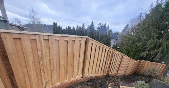 A wooden fence in a backyard with trees in the background