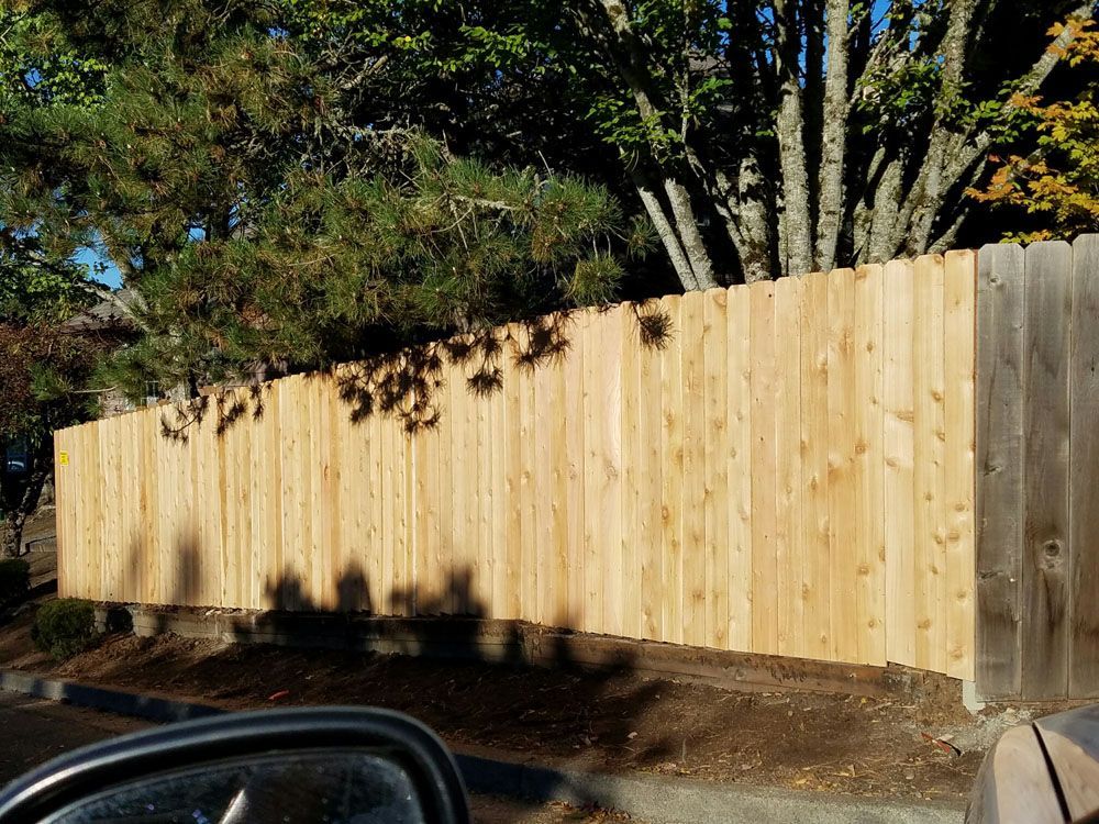 A wooden fence with a lattice design is sitting next to a sidewalk