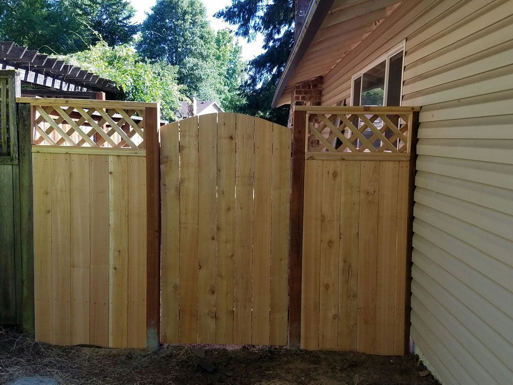 A wooden fence with a lattice design is next to a house
