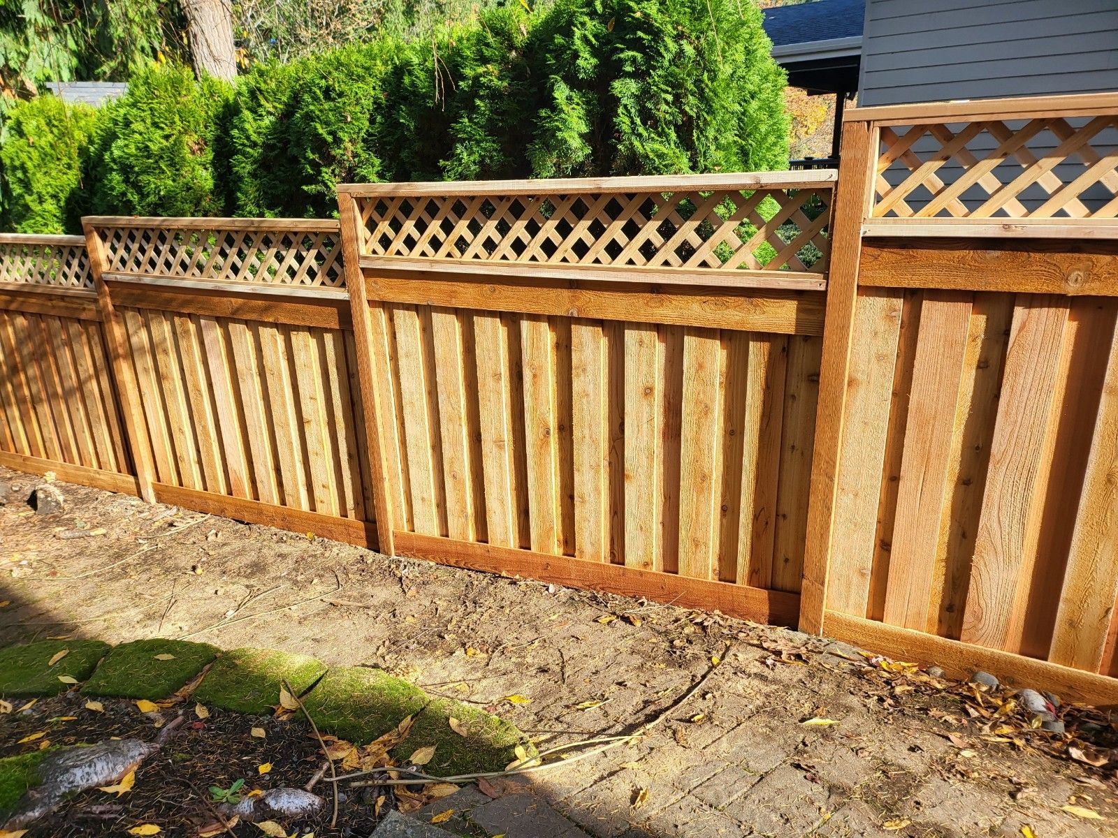A wooden fence with a lattice top is in the backyard of a house
