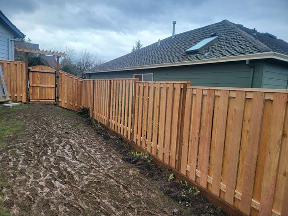 A wooden fence with a gate in the backyard of a house